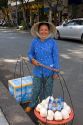 Vietnamese woman selling coconuts and bottled water on the street in Ho Chi Minh City, Vietnam.