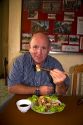 American man eating a spring roll with chopstix in Quang Tri Province, Vietnam.