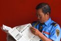 Vietnamese security guard reading a newspaper in Ho Chi Minh City, Vietnam.