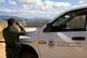 United States Border Patrol agent using binoculars to survey the new border fence that prevents illegal immagrant crossings at the U.S./Mexico border near San Diego, California