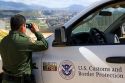 United States Border Patrol agent using binoculars to survey the new border fence that prevents illegal immagrant crossings at the U.S./Mexico border near San Diego, California