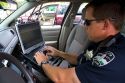 Police officer using a mobile data terminal computer inside a police car in Boise, Idaho, USA.