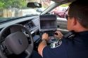 Police officer using a mobile data terminal computer inside a police car in Boise, Idaho, USA.