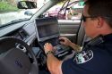 Police officer using a mobile data terminal computer inside a police car in Boise, Idaho, USA.