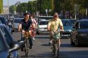 People ride bicycles along the Avenue des Champs-Elysees in Paris, France.
