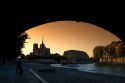 View of the Notre Dame cathedral at sunset through the arch of the Tournelle Bridge on the River Seine in Paris, France.