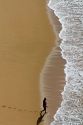 Man walking on the beach into the surf at Acapulco, Guerrero, Mexico.