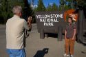 Tourists take a photo in front of the Yellowstone National Park entrance sign, West Yellowstone, Montana, USA.