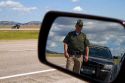 Wyoming Highway Patrol officer on seen in rear-view mirror along I-90 near the Wyoming, South Dakota border, USA. MR