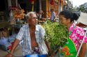 Grocer smelling fresh bay leaves being offered for sale by the grower on the island of Ko Samui, Thailand.