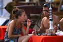 Tourists smoke flavored tobacco out of a hookah at Chaweng beach in the Gulf of Thailand on the island of Ko Samui, Thailand.