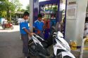 Gas station attendent filling up a motor scooter on the island of Ko Samui, Thailand.